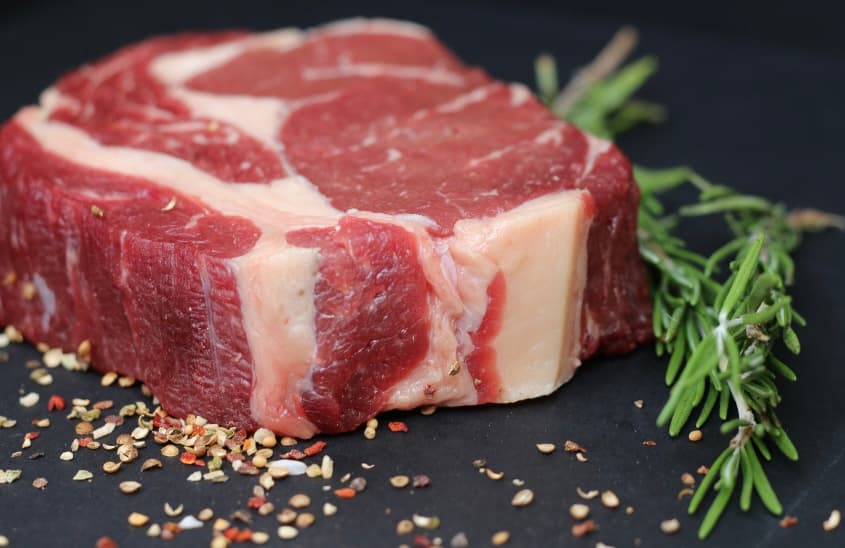 Thick-cut marbled ribeye steak with rosemary and cracked peppercorns