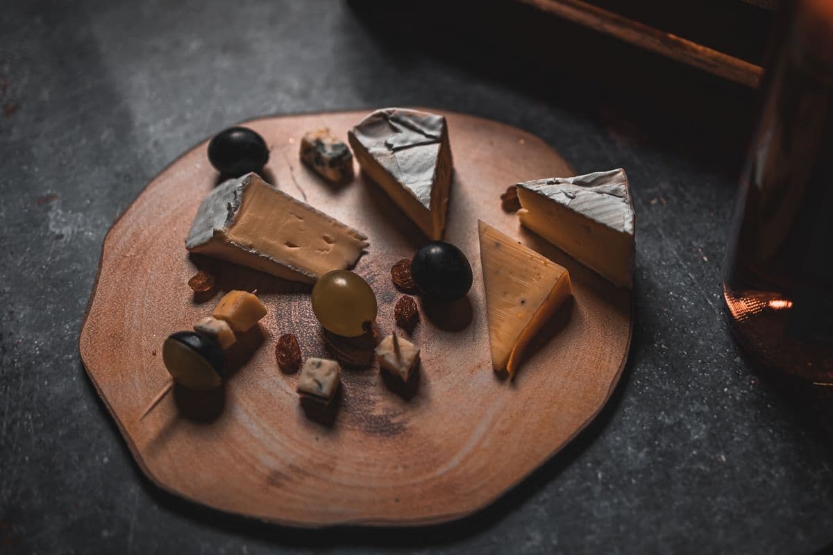 Assorted cheese wedges with grapes on a rustic wooden board